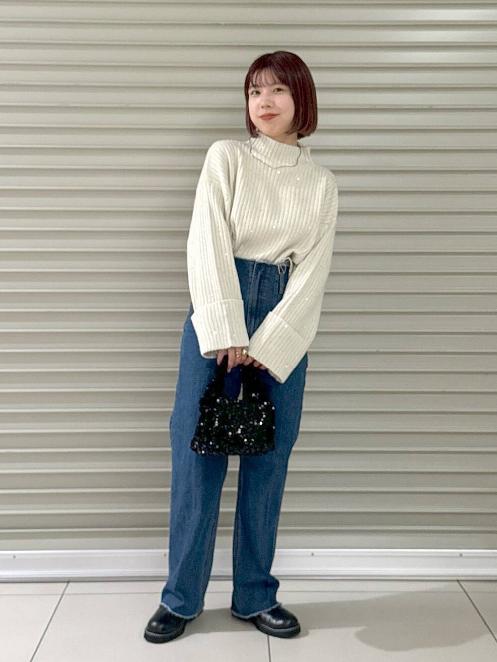 ブルー系のデニムパンツ、ブラック系のブーツ、ブラック系のハンドバッグを着用したレディースの秋コーディネートの2枚目の写真