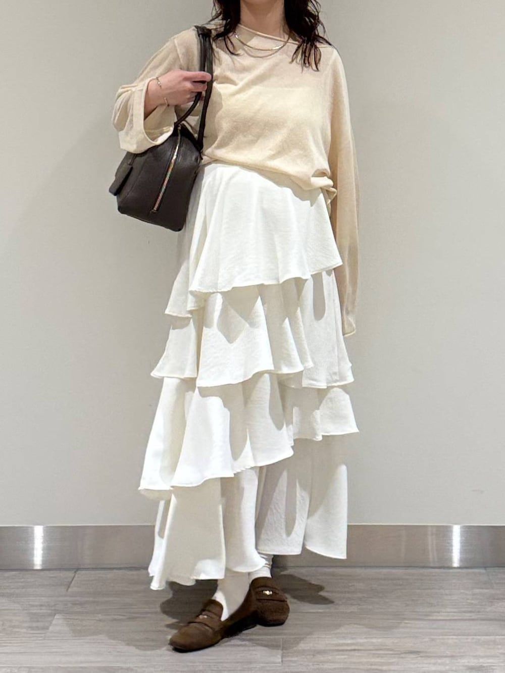 ホワイト系のニット/セーター、ブラウン系のハンドバッグ、ブラウン系のローファーを着用したレディースの春コーディネートの2枚目の写真