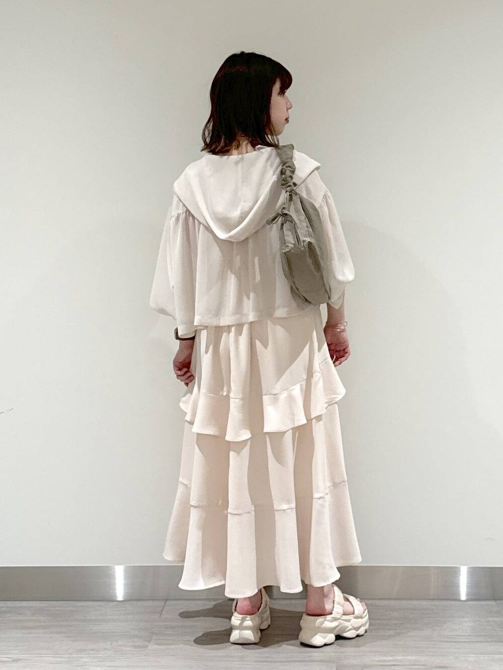 ブラウン系のショルダーバッグ、ベージュ系のキャミソール、ホワイト系のパーカーを着用したレディースの夏コーディネートの2枚目の写真