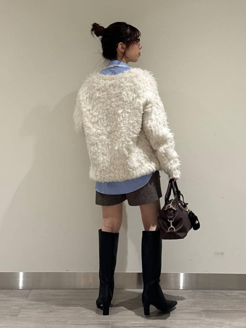 ブラウン系のボストンバッグ、ホワイト系のカーディガン/ボレロ、ブラウン系のその他パンツを着用したレディースの冬コーディネートの3枚目の写真