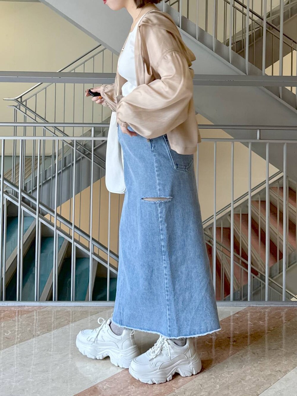 ホワイト系のトートバッグ、ベージュ系のパーカー、ホワイト系のスニーカーを着用したレディースの冬コーディネートの3枚目の写真