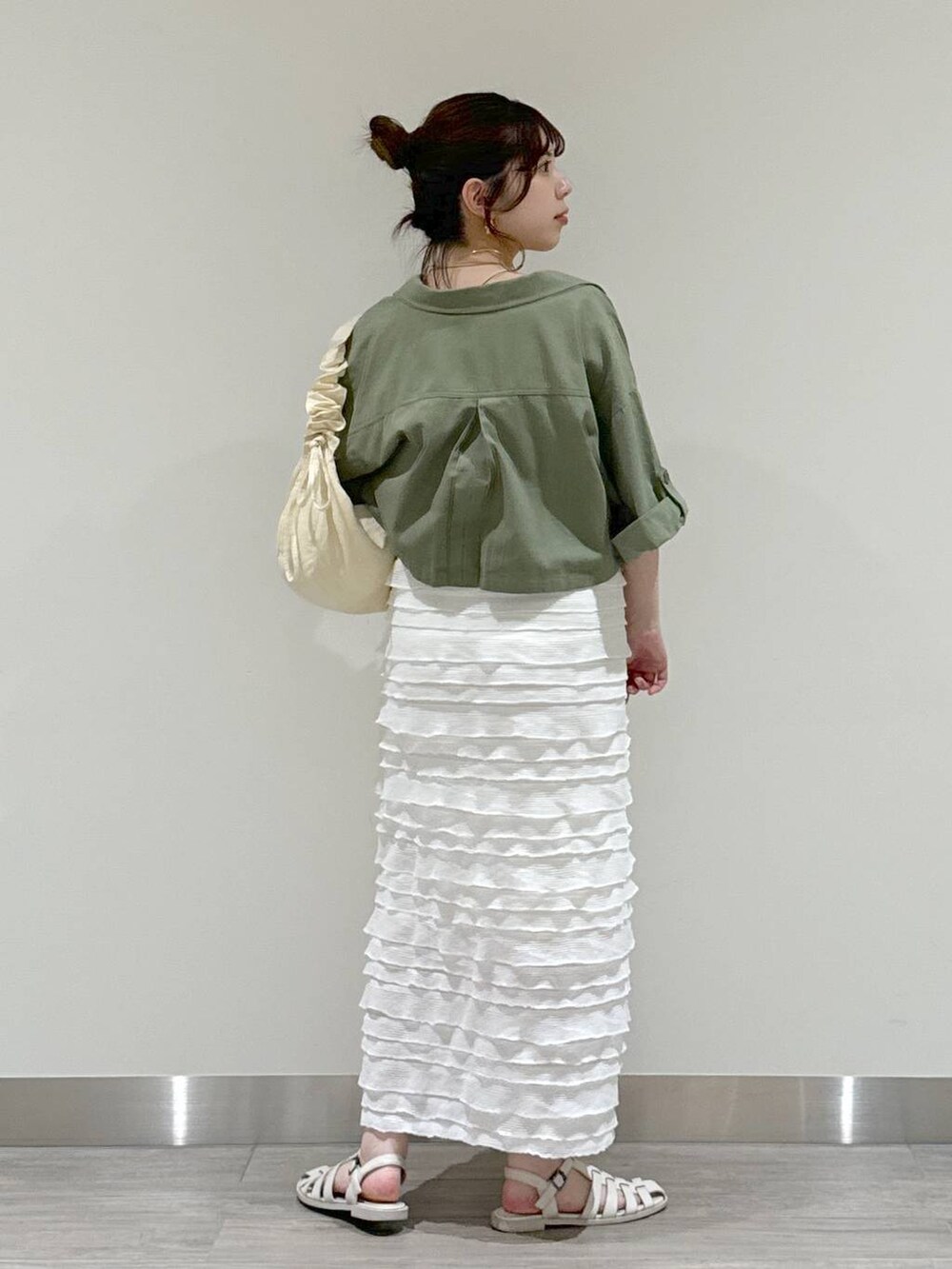 ホワイト系のショルダーバッグ、ベージュ系のキャミソール、グリーン系のミリタリージャケットを着用したレディースの夏コーディネートの2枚目の写真