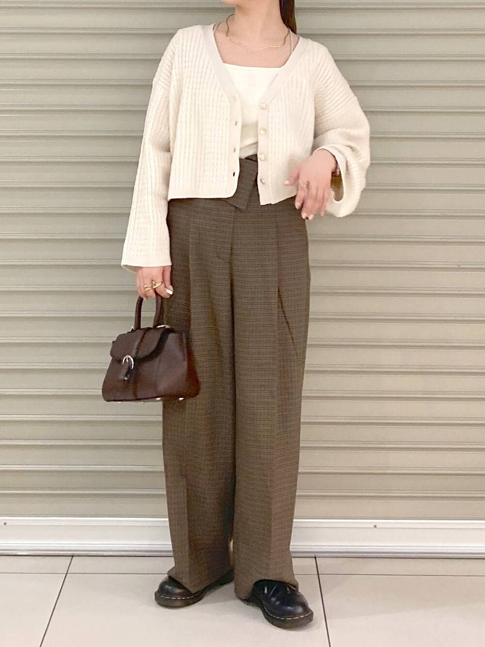 ホワイト系のタンクトップ、ブラウン系のハンドバッグ、ホワイト系のカーディガン/ボレロを着用したレディースの秋コーディネートの2枚目の写真
