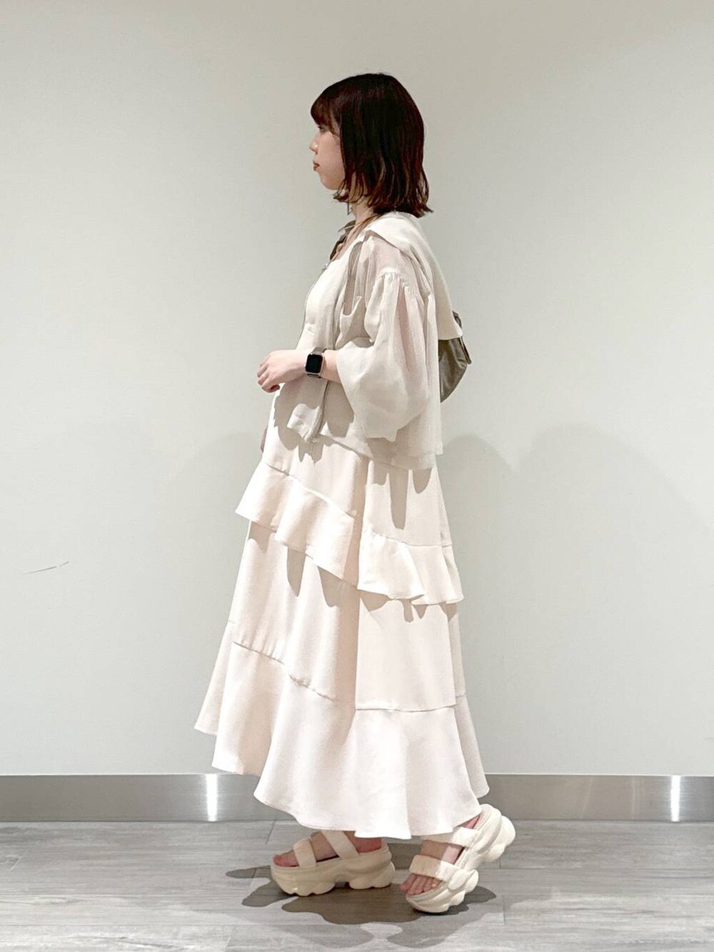 ブラウン系のショルダーバッグ、ベージュ系のキャミソール、ホワイト系のパーカーを着用したレディースの夏コーディネートの3枚目の写真