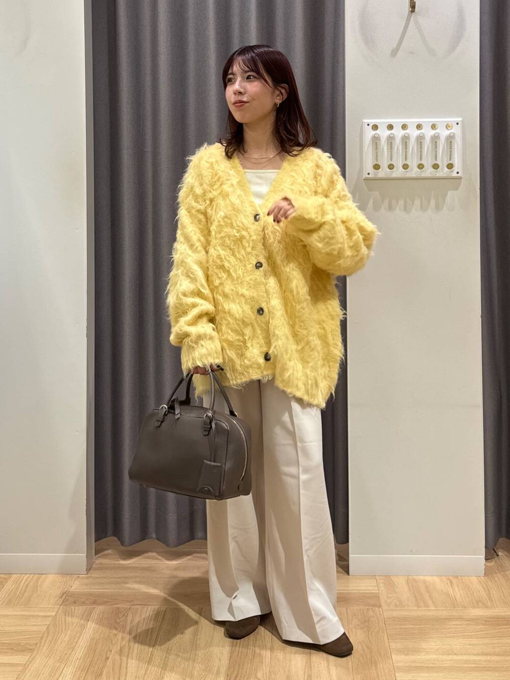 ブラウン系のハンドバッグ、イエロー系のカーディガン/ボレロ、ブラウン系のローファーを着用したレディースの秋コーディネートの2枚目の写真