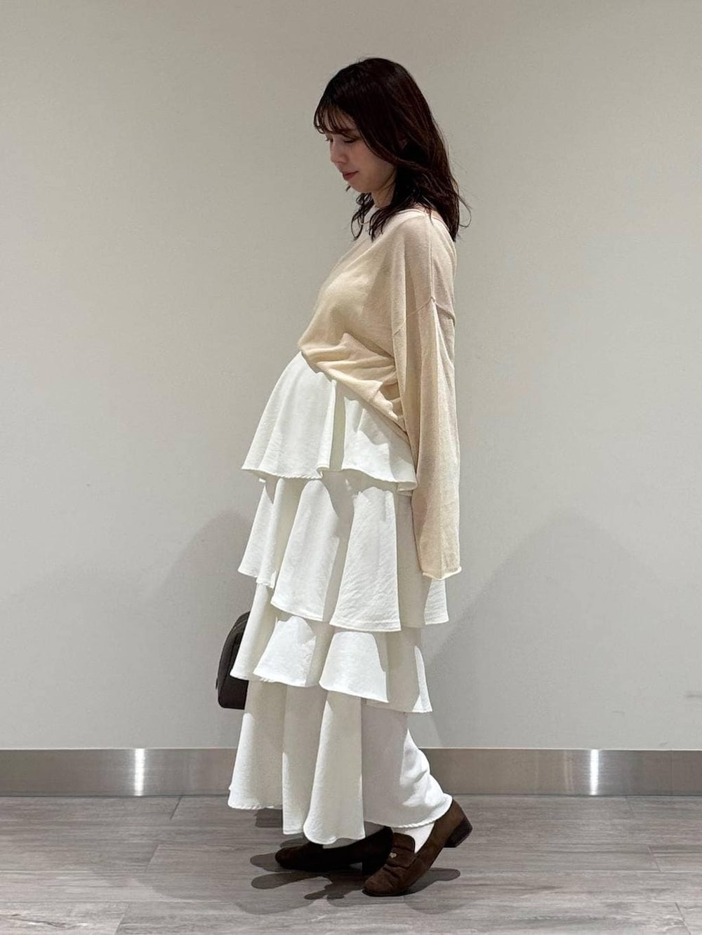 ホワイト系のニット/セーター、ブラウン系のハンドバッグ、ブラウン系のローファーを着用したレディースの春コーディネートの3枚目の写真