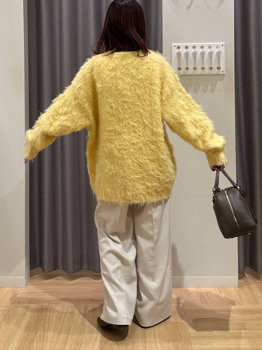 ブラウン系のハンドバッグ、イエロー系のカーディガン/ボレロ、ブラウン系のローファーを着用したレディースの秋コーディネートの3枚目の写真