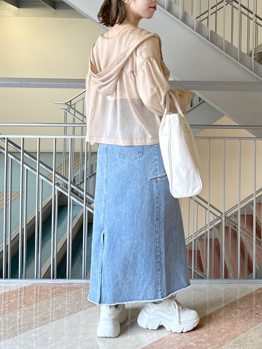 ホワイト系のトートバッグ、ベージュ系のパーカー、ホワイト系のスニーカーを着用したレディースの冬コーディネートの2枚目の写真