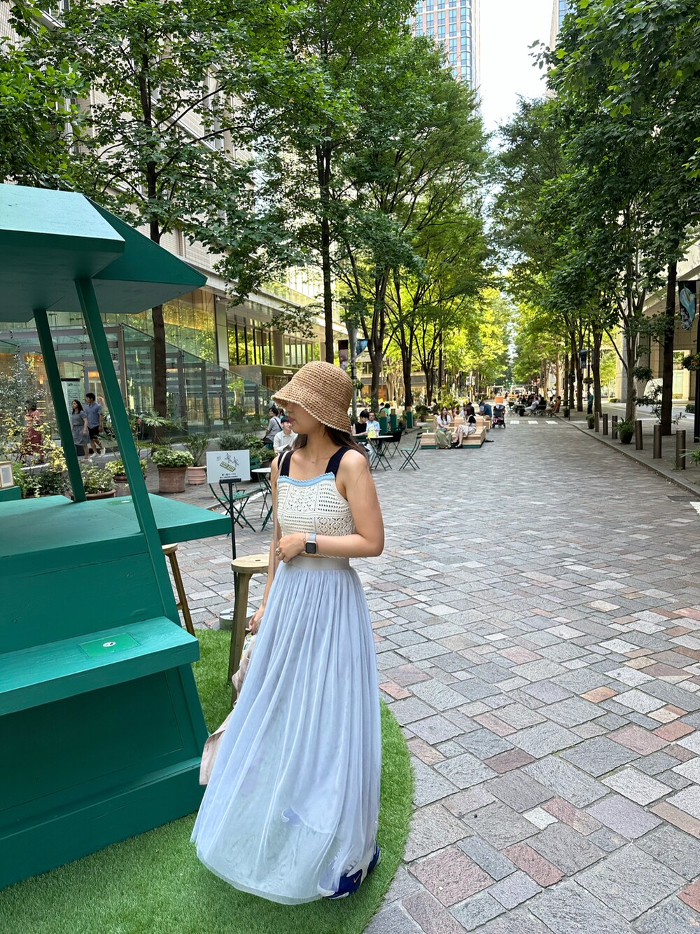 ブルー系のスカート、ホワイト系のタンクトップ、ベージュ系のショルダーバッグを着用したレディースの夏コーディネートの2枚目の写真