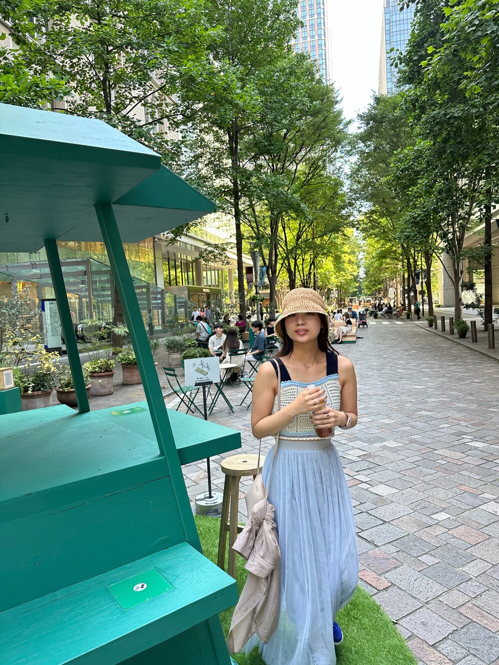 ブルー系のスカート、ホワイト系のタンクトップ、ベージュ系のショルダーバッグを着用したレディースの夏コーディネートの3枚目の写真