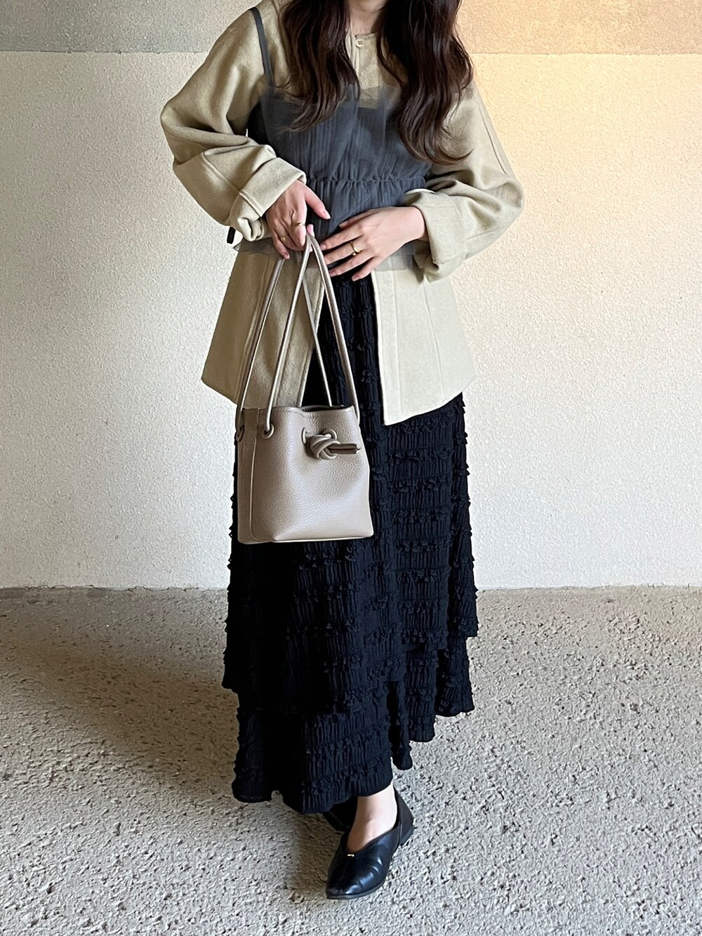グレー系のチューブトップ、グレー系のバッグ、ブラック系のスカートを着用したレディースの秋コーディネートの2枚目の写真