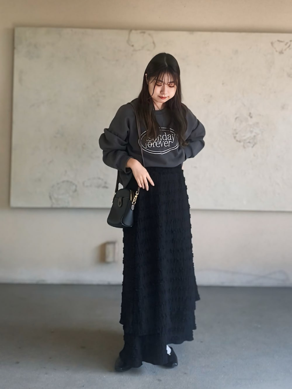 ブラック系のスカート、グレー系のトップス、ブラック系のパンプスを着用したレディースの秋コーディネートの2枚目の写真