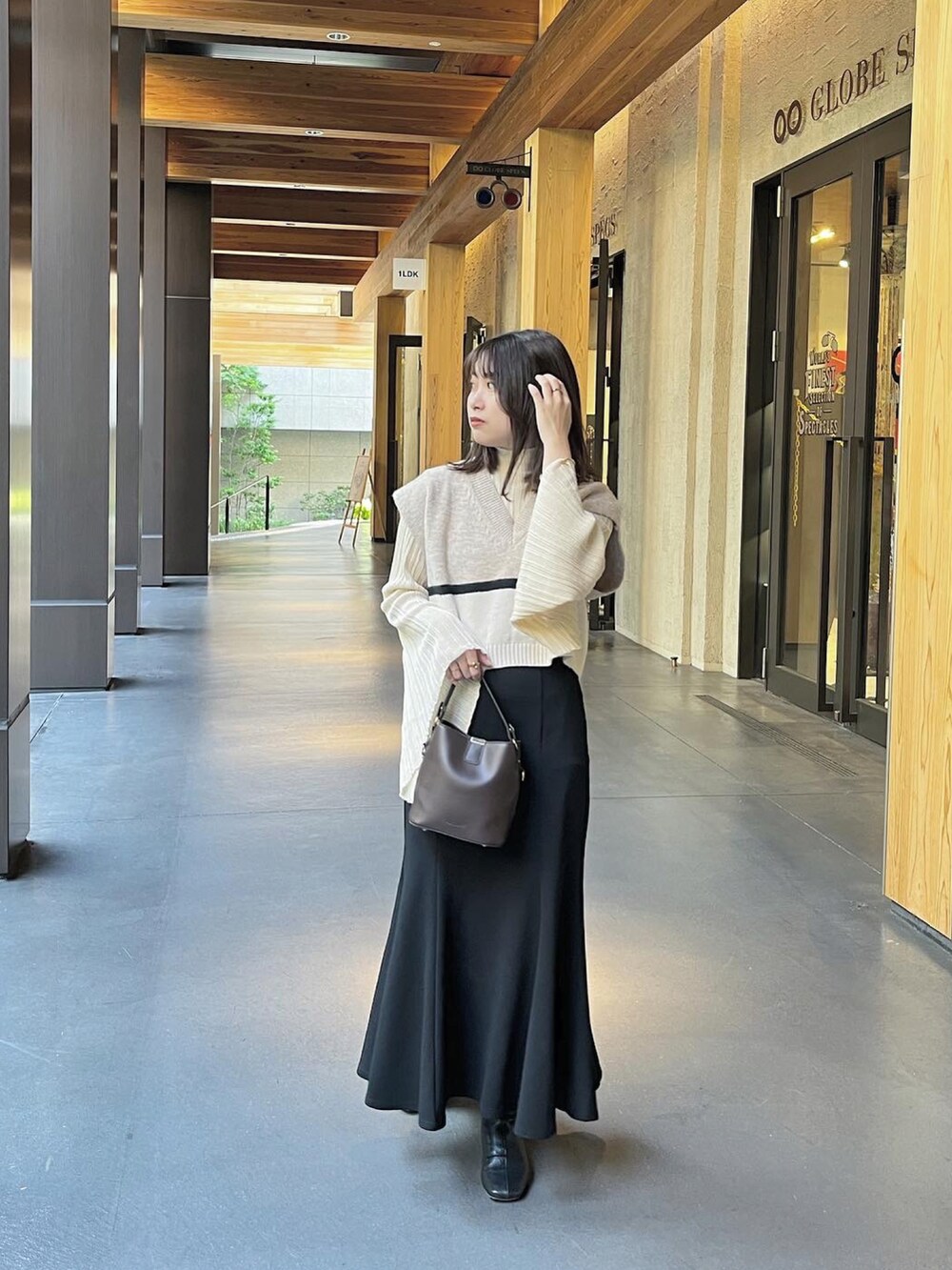 ブラウン系のショルダーバッグ、ブラック系のスカートを着用したレディースの冬コーディネートの2枚目の写真