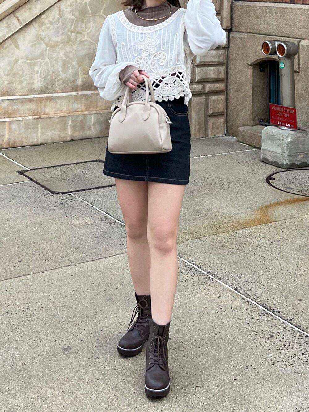 ブラック系のデニムスカート、ベージュ系のシャツ/ブラウス、ブラウン系のニット/セーターを着用したレディースの春コーディネートの3枚目の写真