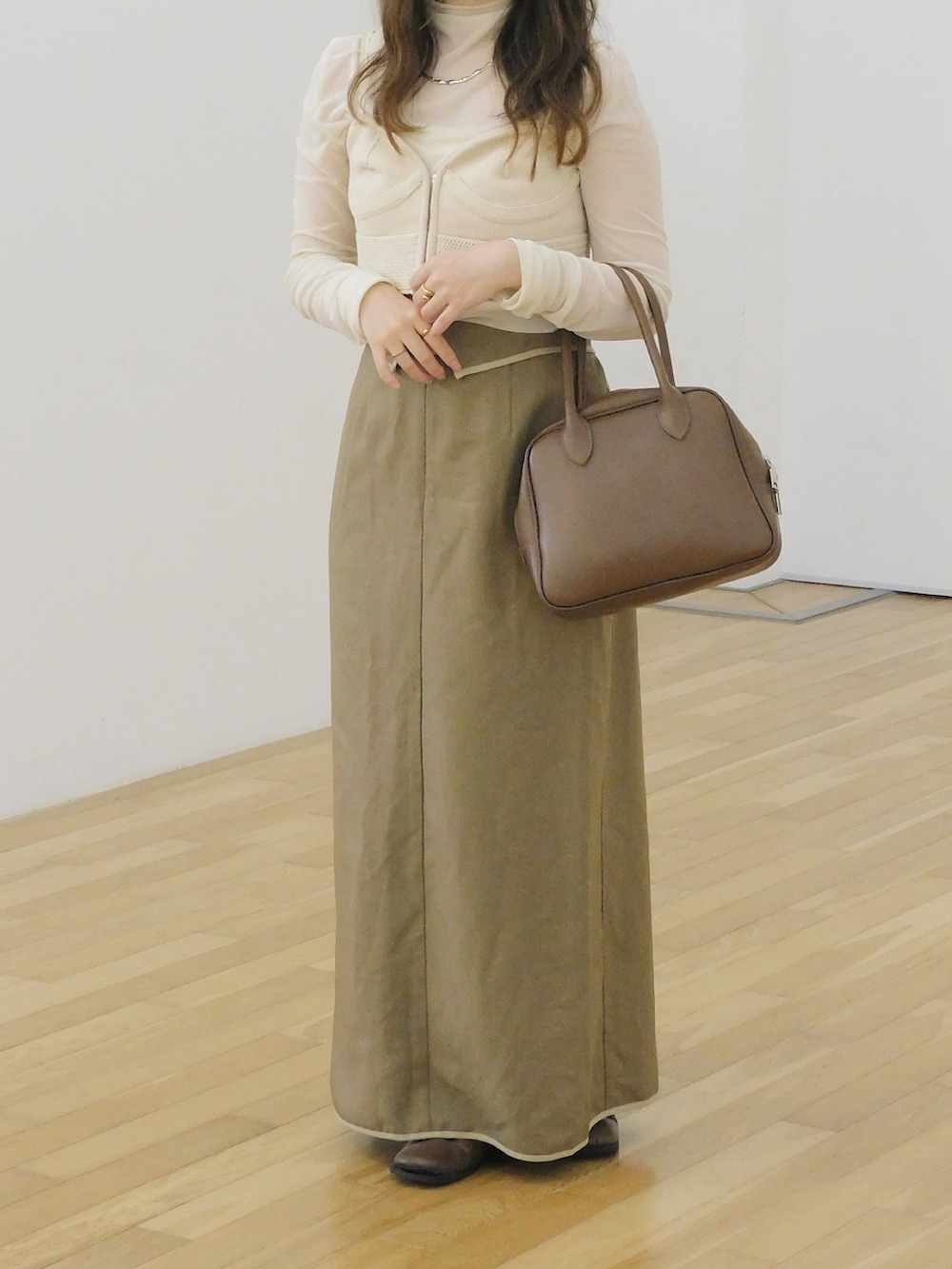 ブラウン系のショルダーバッグ、ベージュ系のベスト、ブラウン系のスカートを着用したレディースの夏コーディネートの2枚目の写真