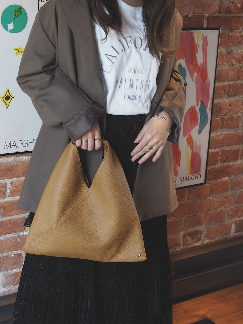 ブラウン系のセットアップ、ブラック系のスカート、ブラウン系のハンドバッグを着用したレディースの秋コーディネートの2枚目の写真