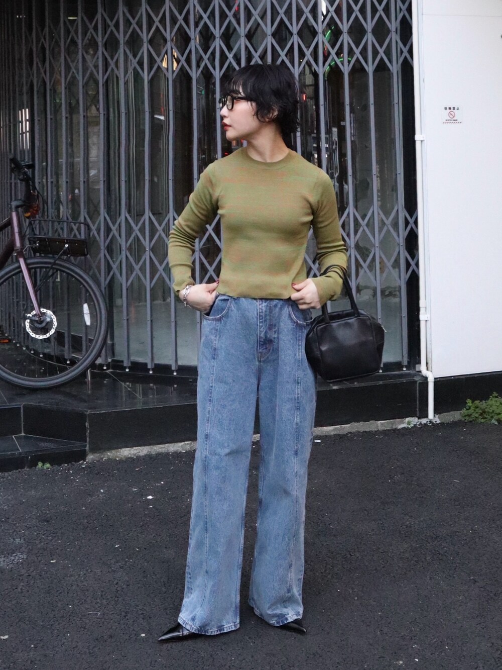 ブルー系のデニムパンツ、ブラック系のパンプス、オレンジ系のニット/セーターを着用したレディースの秋コーディネートの2枚目の写真