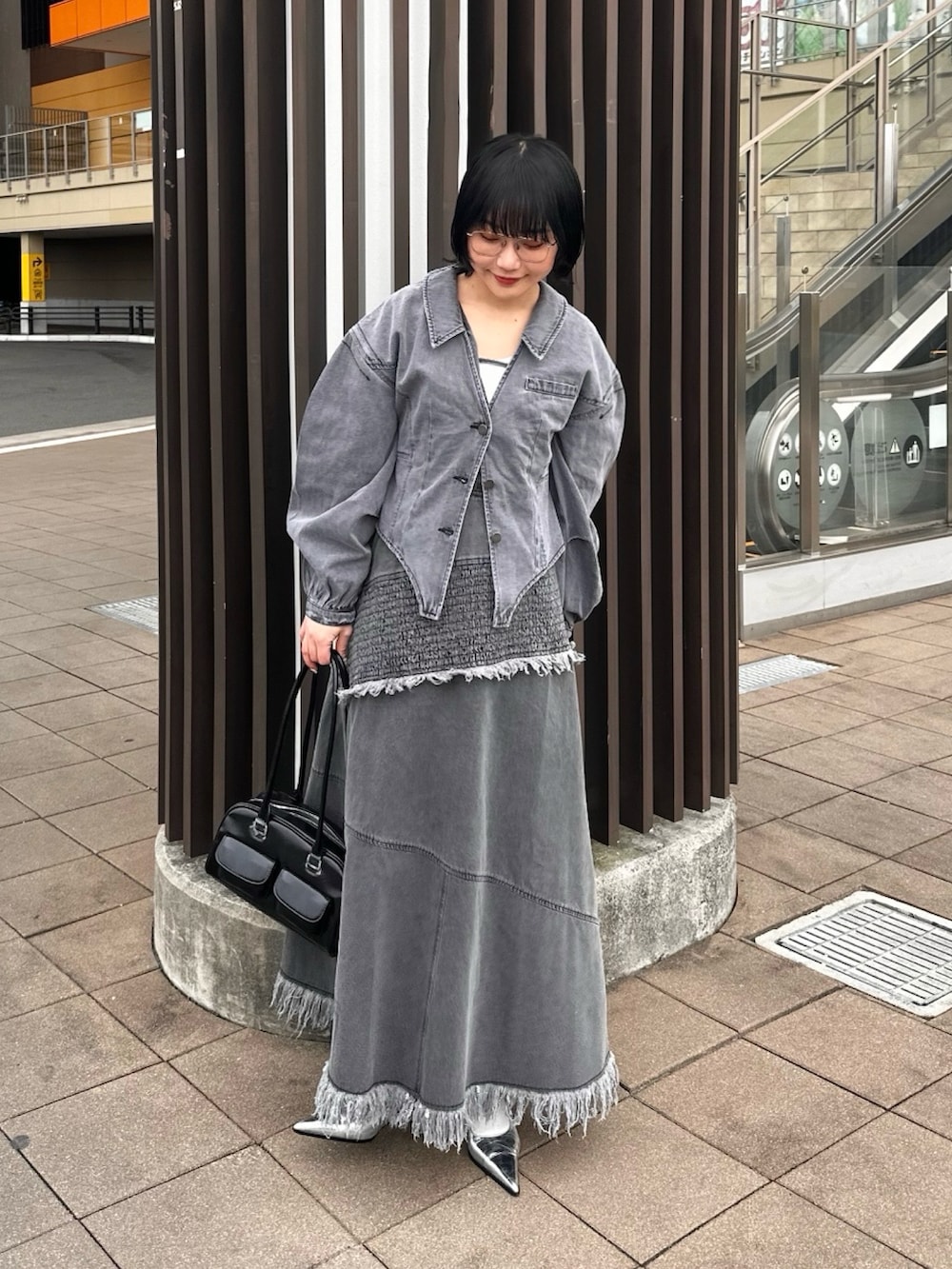 グレー系のワンピース、グレー系のデニムジャケット、シルバー系のパンプスを着用したレディースの春コーディネートの2枚目の写真