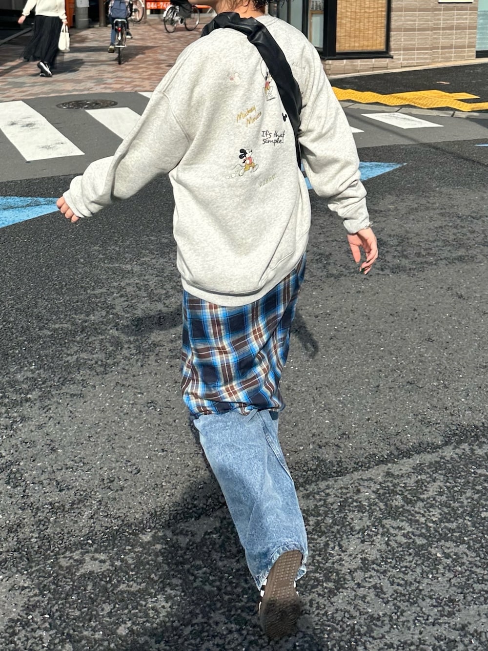 グレー系のスウェット、ブルー系のスカート、ブルー系のデニムパンツを着用したレディースの秋コーディネートの4枚目の写真