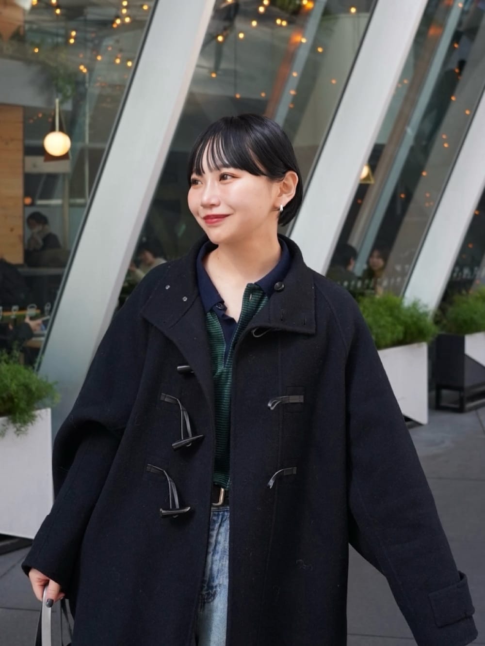 グリーン系のポロシャツ、ブラック系のダッフルコート、ブルー系のパンツを着用したレディースの冬コーディネートの2枚目の写真