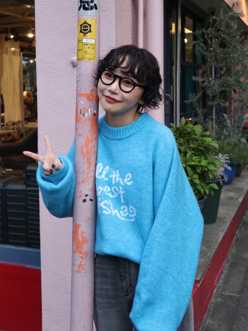 ブラック系のデニムパンツ、ブルー系のニット/セーター、グレー系のスニーカーを着用したレディースの秋コーディネートの2枚目の写真