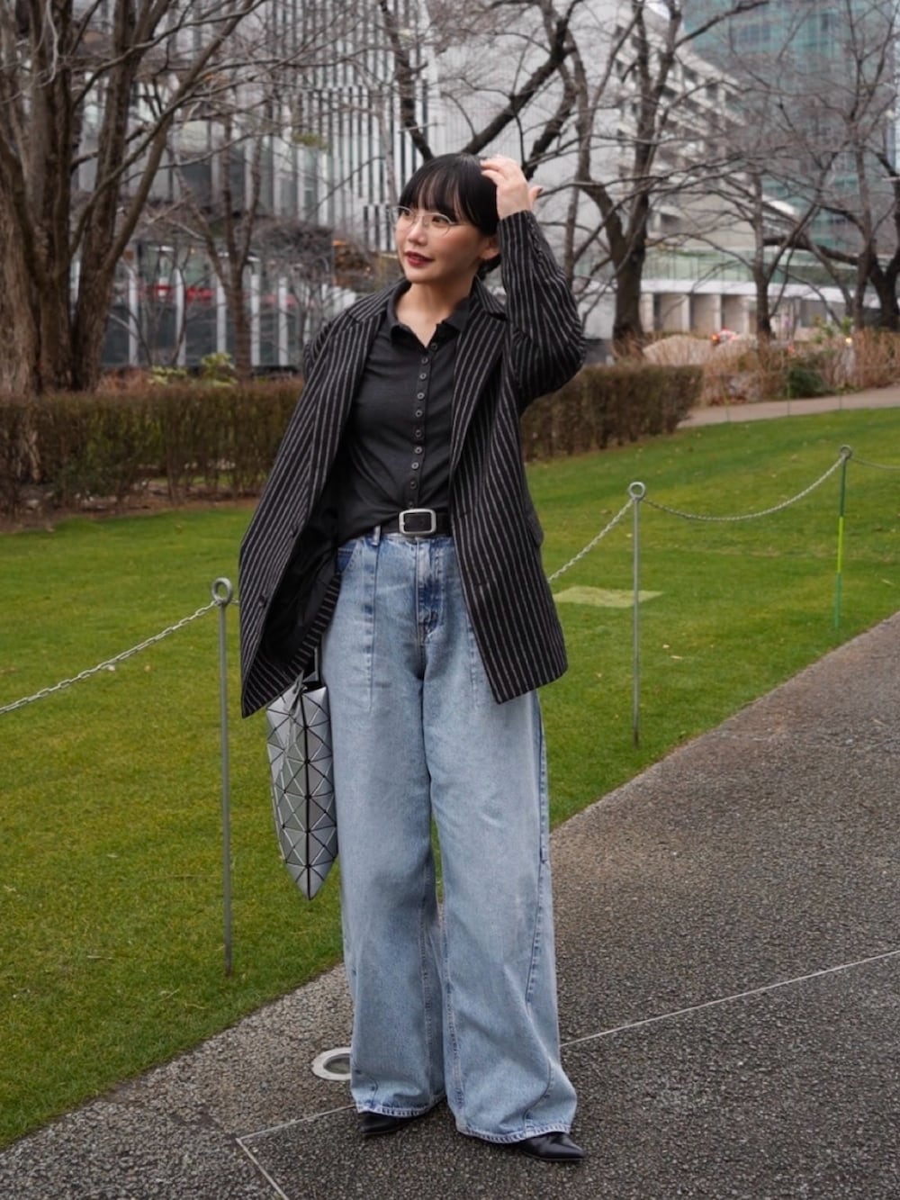 グレー系のTシャツ/カットソー、ブラック系のテーラードジャケット、ブルー系のデニムパンツを着用したレディースの冬コーディネートの2枚目の写真