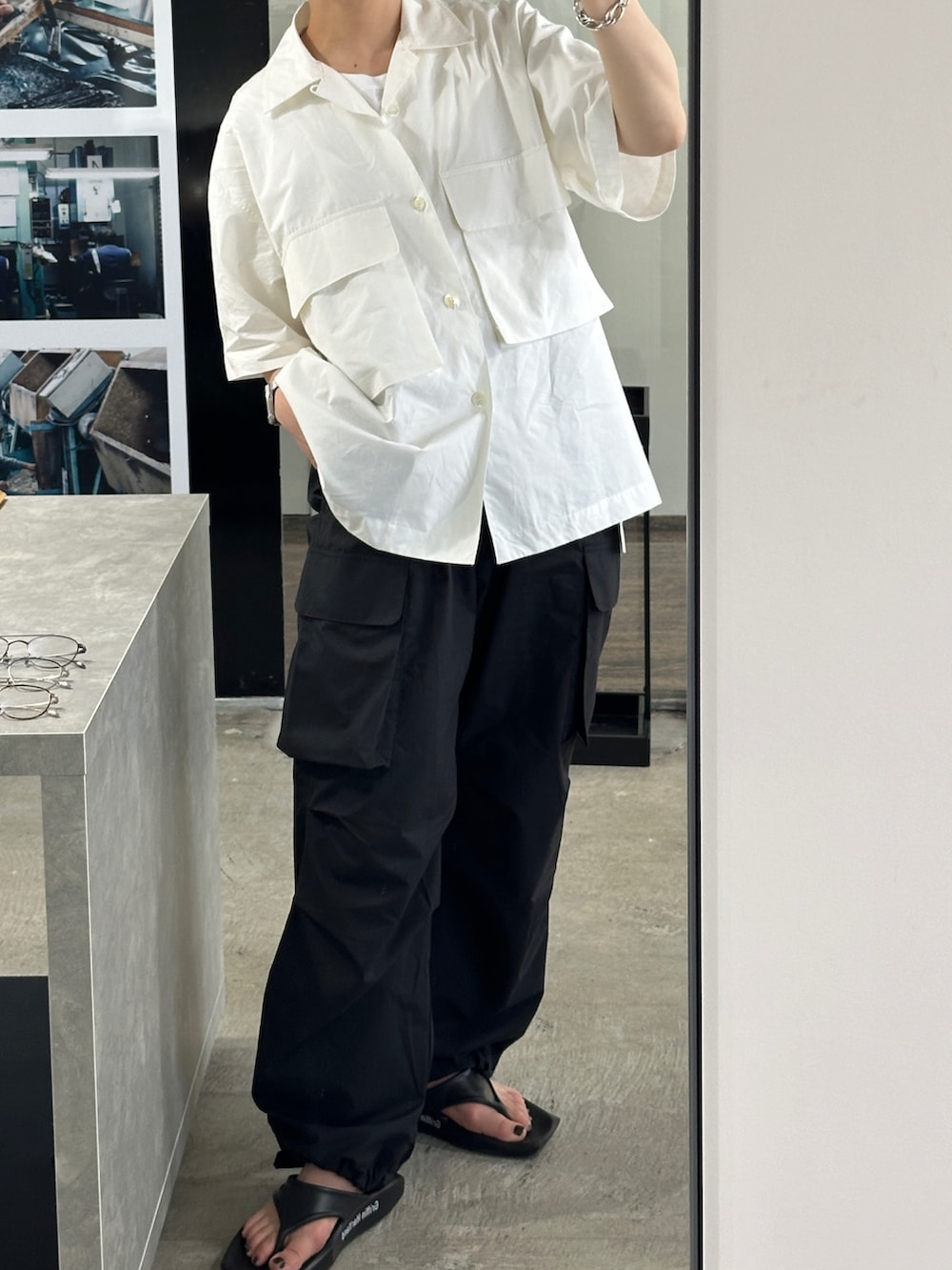 ブラック系のパンツ、ホワイト系のトップス、シルバー系のブレスレットを着用したレディースの夏コーディネートの2枚目の写真