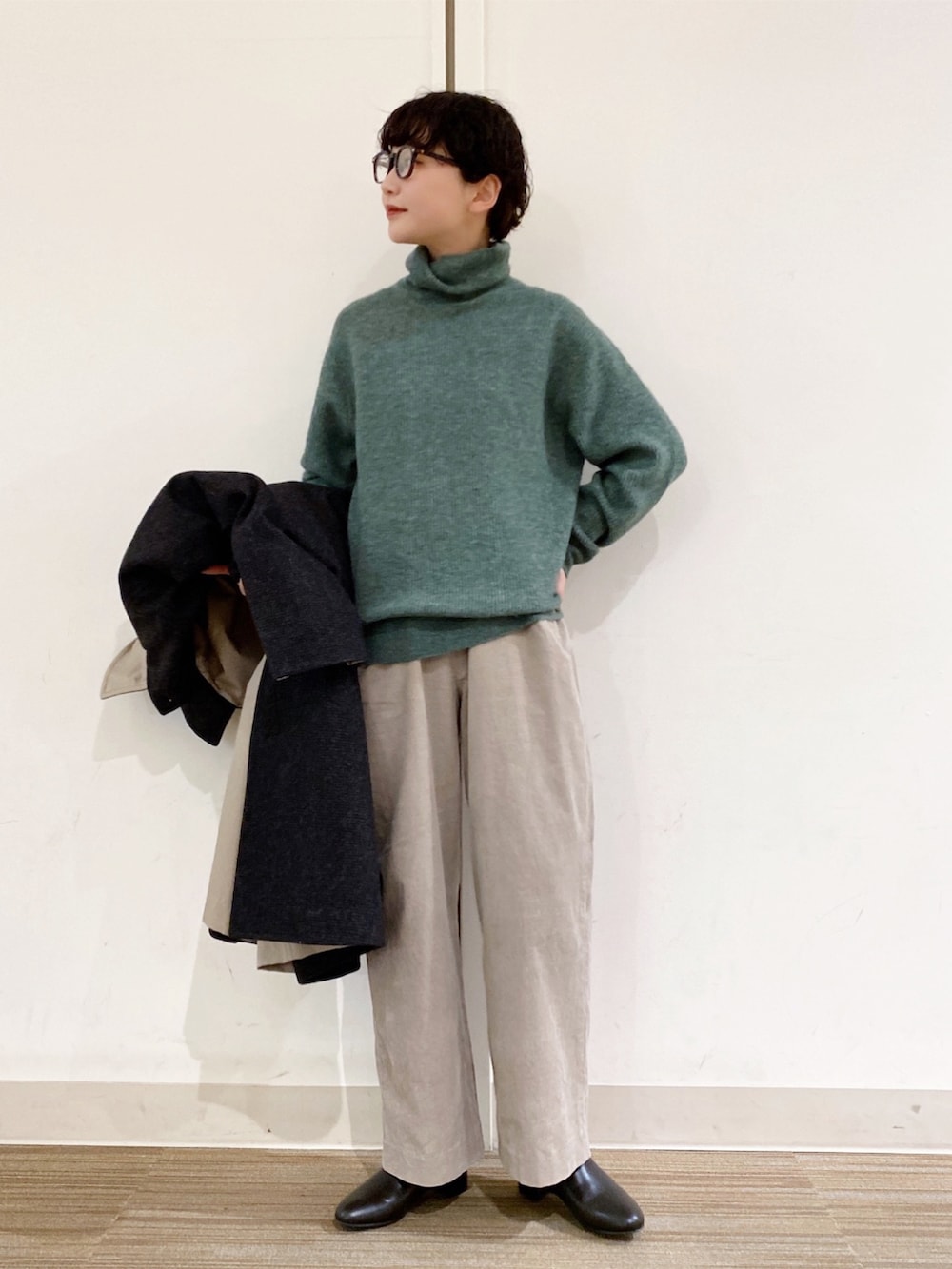 グリーン系のニット/セーター、グレー系のその他パンツ、グレー系のステンカラーコートを着用したレディースの冬コーディネートの2枚目の写真