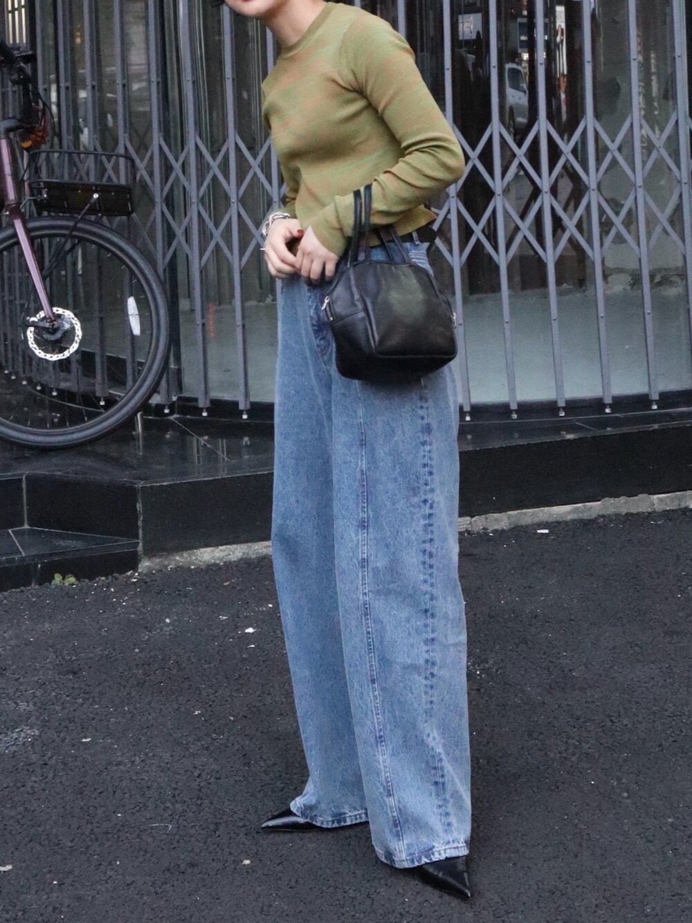 ブルー系のデニムパンツ、ブラック系のパンプス、オレンジ系のニット/セーターを着用したレディースの秋コーディネートの3枚目の写真