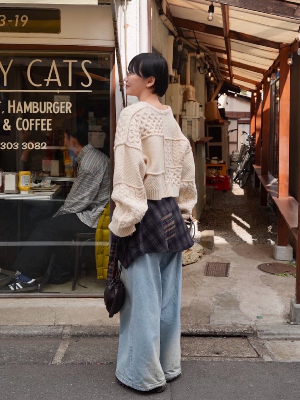 ホワイト系のトップス、ブルー系のデニムパンツ、ブラック系のデニムパンツを着用したレディースの冬コーディネートの3枚目の写真