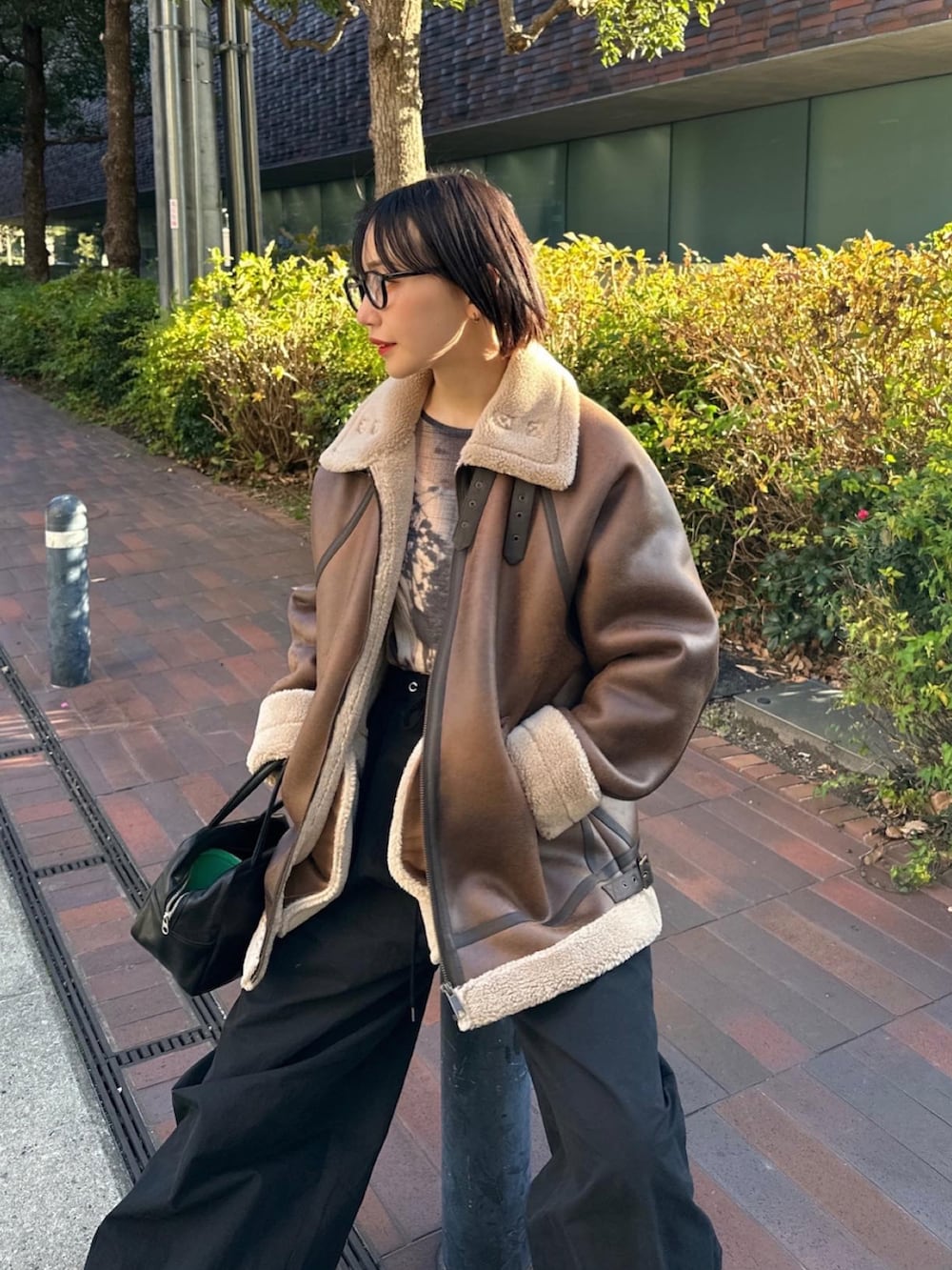 ブラウン系のムートンコート、ブラック系のその他パンツ、ブラック系のブーツを着用したレディースの冬コーディネートの3枚目の写真