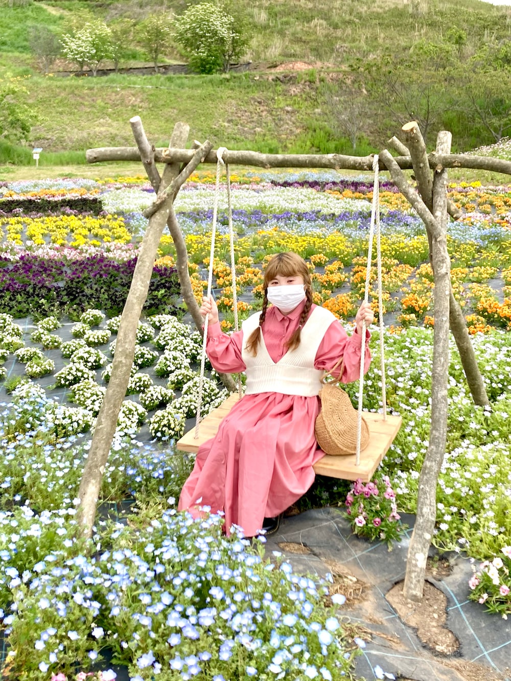 ホワイト系のベスト、ピンク系のシャツワンピース、ベージュ系のトートバッグを着用したレディースの春コーディネートの2枚目の写真