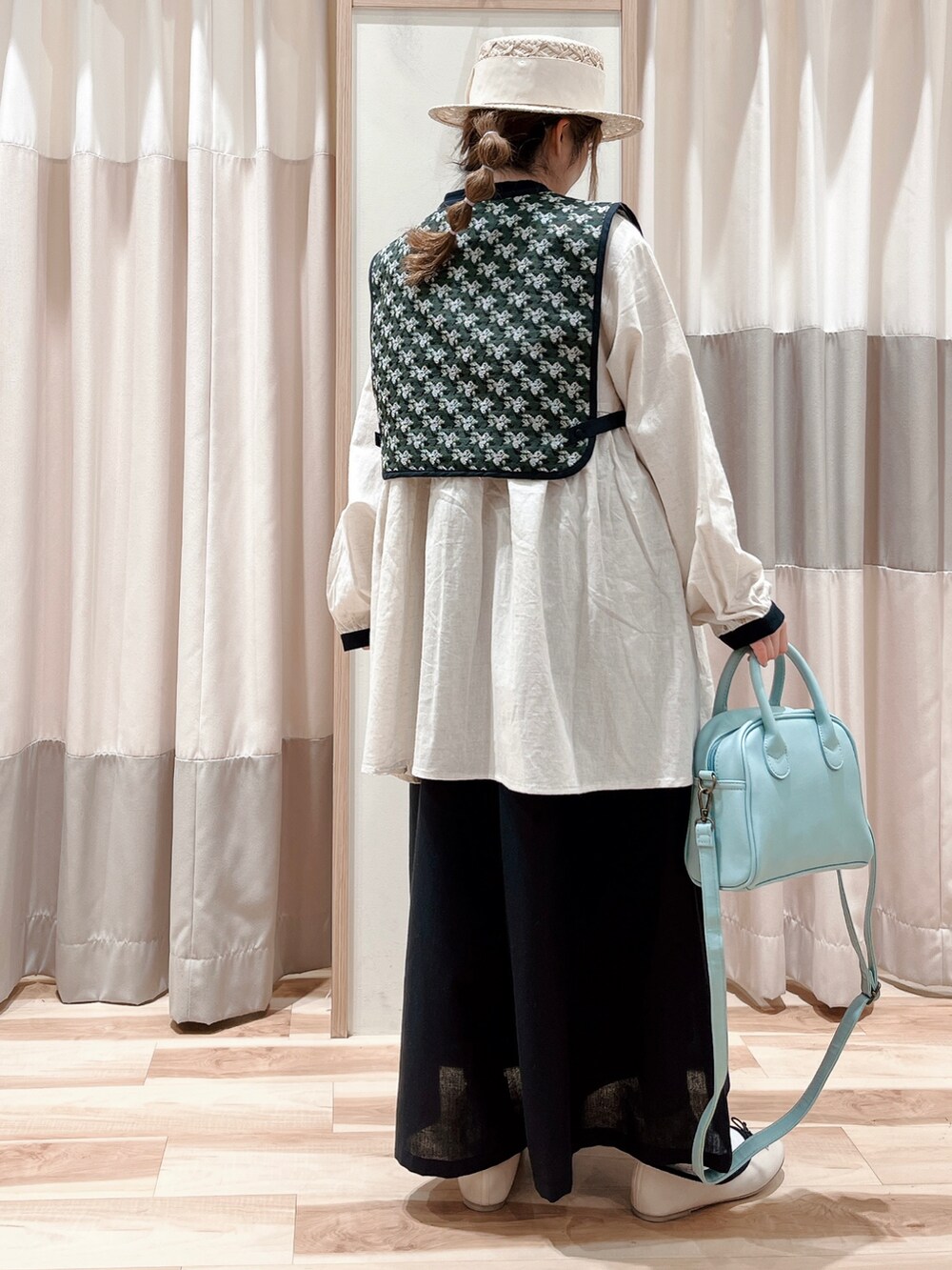 グレー系のベスト、ホワイト系のチュニック、ブラック系のその他パンツを着用したレディースの春コーディネートの2枚目の写真