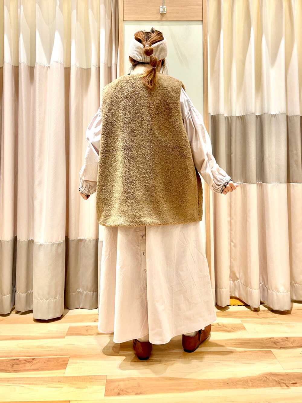 ピンク系のワンピース、ブラウン系のベスト、ベージュ系のTシャツ/カットソーを着用したレディースの秋コーディネートの2枚目の写真