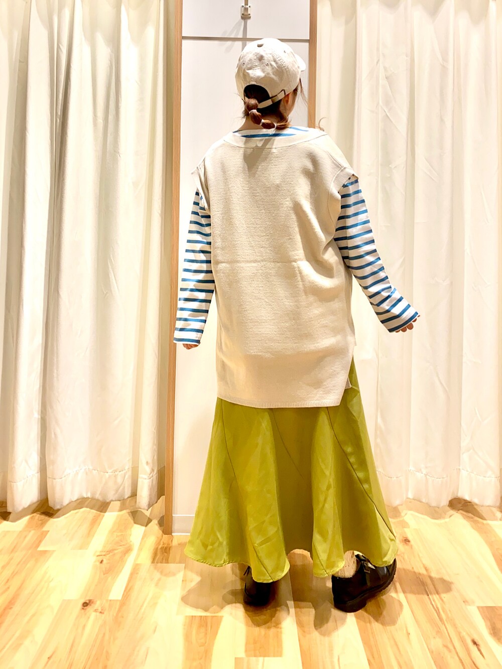 ベージュ系のベスト、グリーン系のTシャツ/カットソー、イエロー系のスカートを着用したレディースの春コーディネートの2枚目の写真