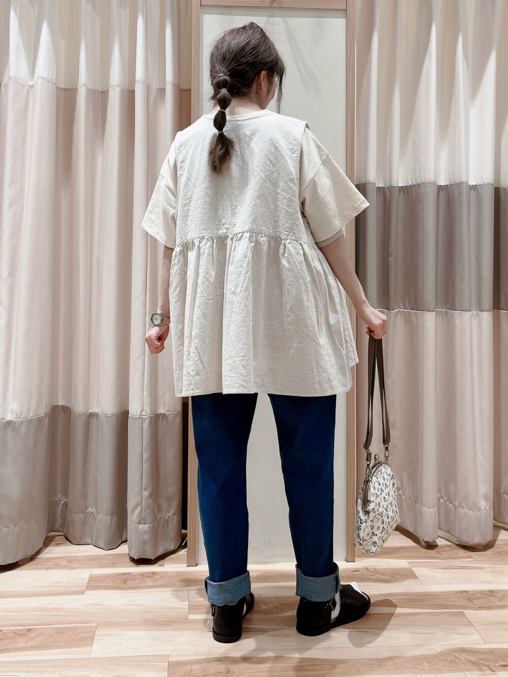 ホワイト系のTシャツ/カットソー、ホワイト系のベスト、ベージュ系のハンドバッグを着用したレディースの春コーディネートの2枚目の写真