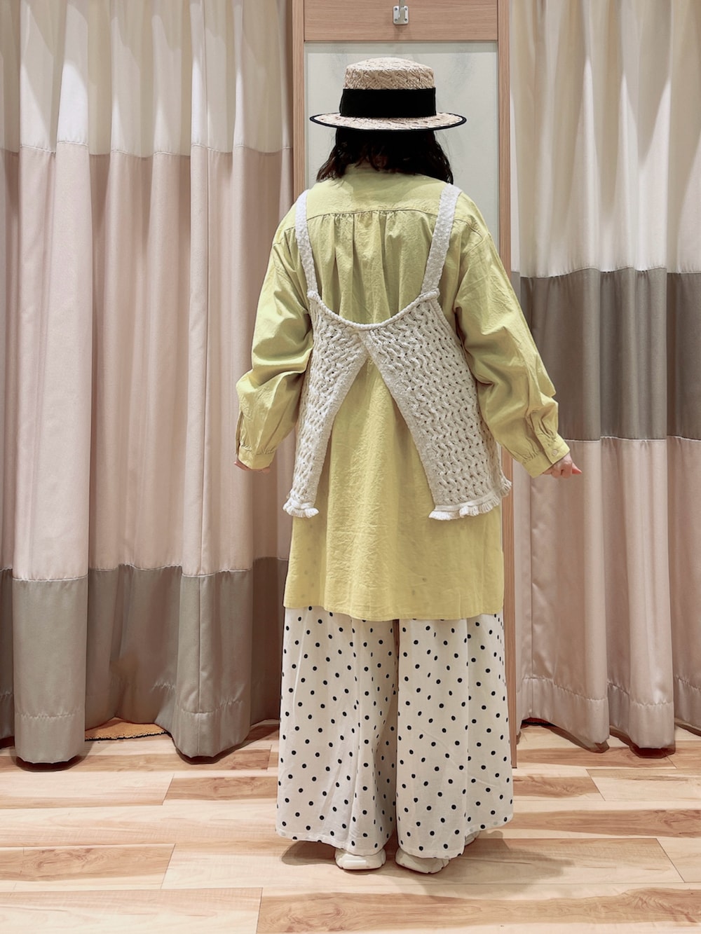 イエロー系のチュニック、ホワイト系のベスト、ホワイト系のその他パンツを着用したレディースの春コーディネートの2枚目の写真