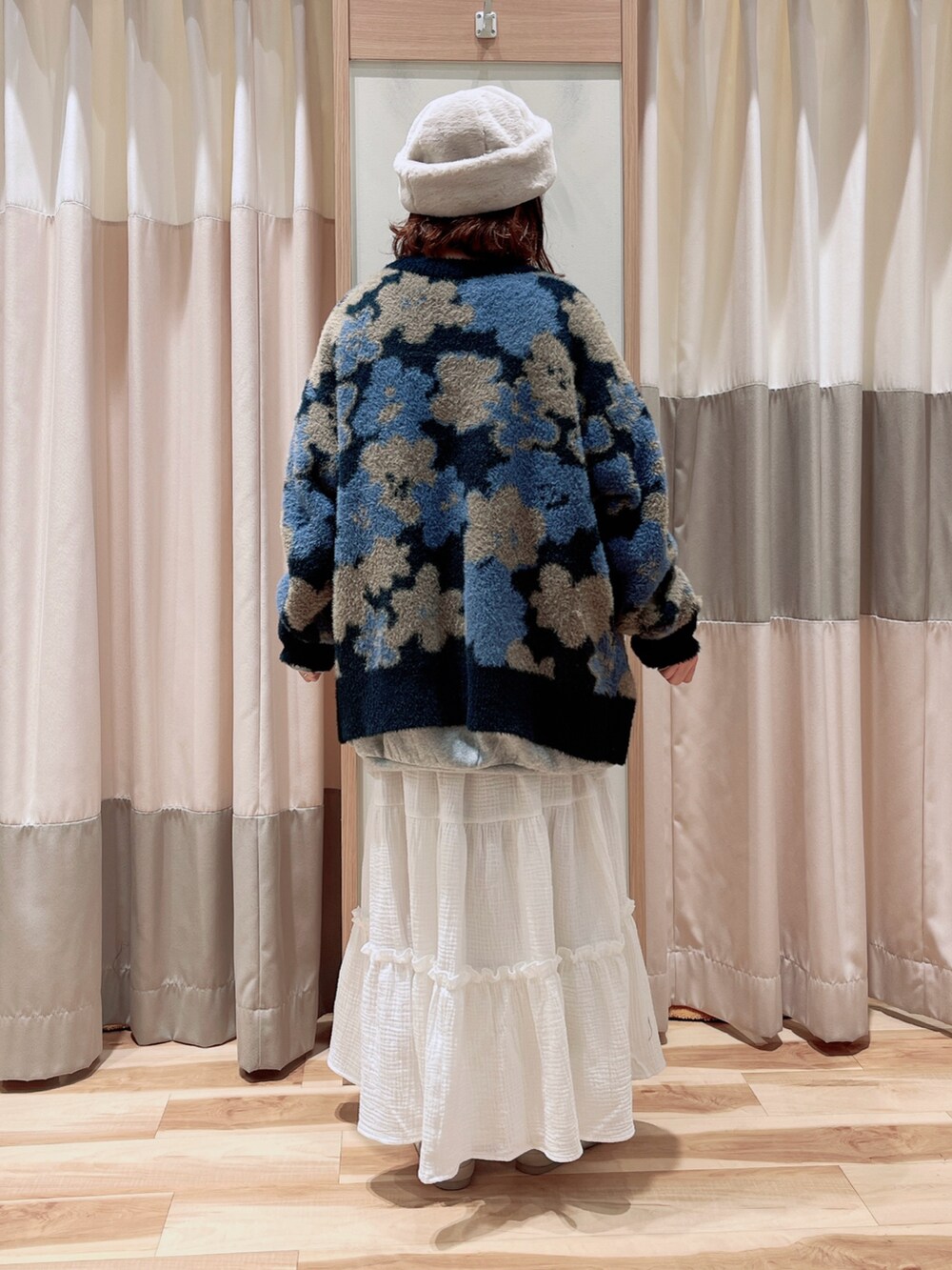 グレー系のTシャツ/カットソー、ブルー系のカーディガン/ボレロ、ホワイト系のスカートを着用したレディースの秋コーディネートの2枚目の写真