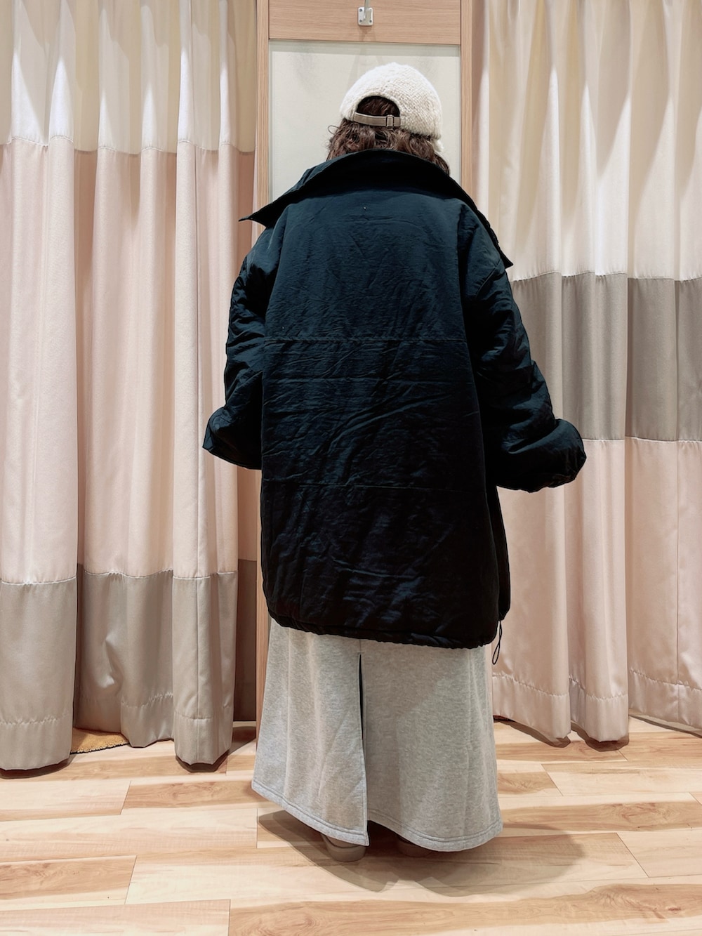 グレー系のワンピース、ホワイト系のニット/セーター、ブラック系のその他アウターを着用したレディースの冬コーディネートの2枚目の写真