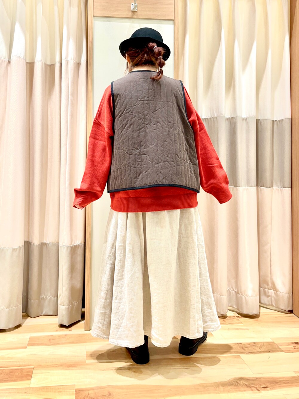 レッド系のニット/セーター、ブラック系のベスト、ホワイト系のスカートを着用したレディースの秋コーディネートの2枚目の写真