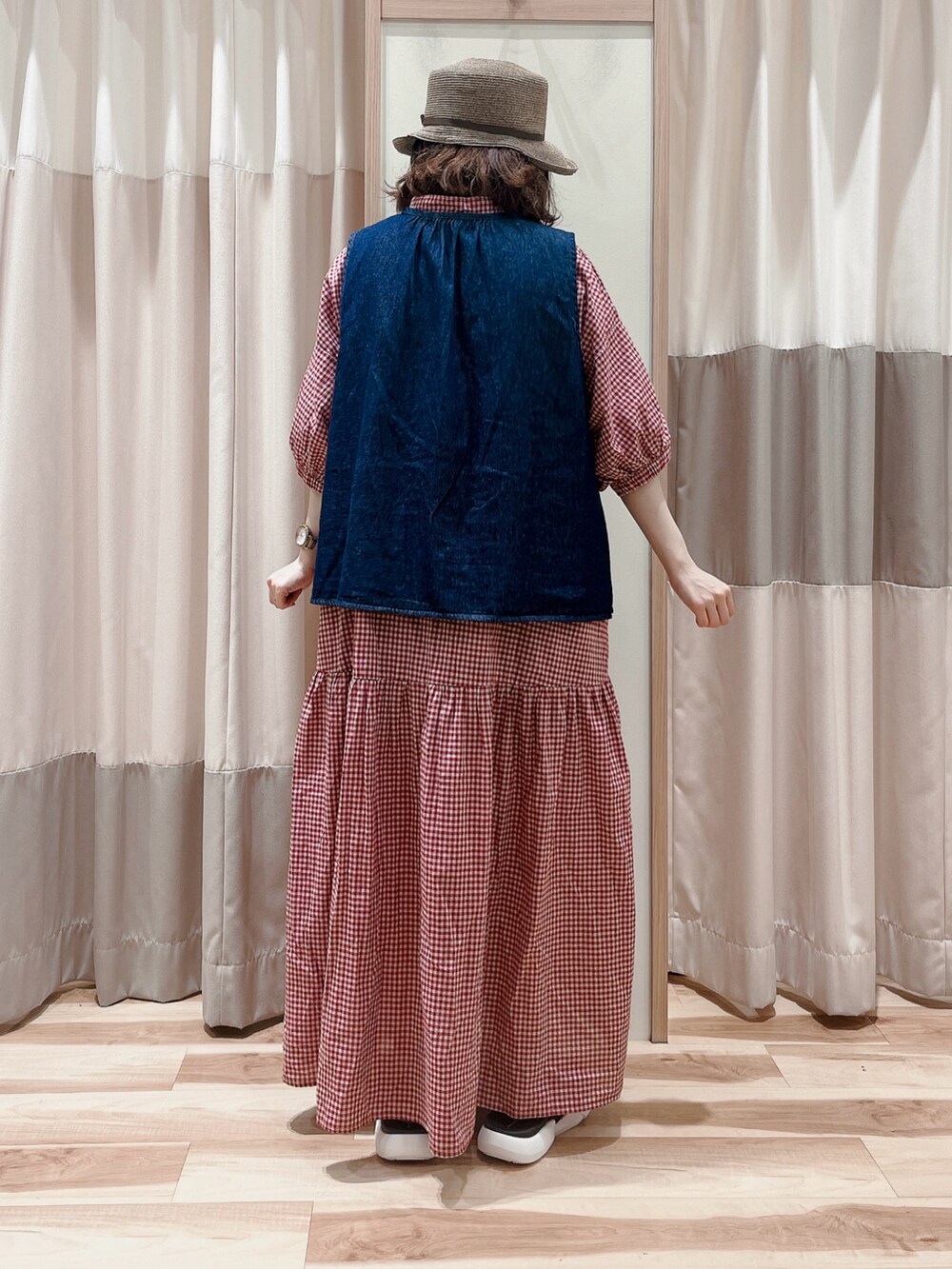 レッド系のワンピース、ブルー系のベスト、ブラック系のサンダルを着用したレディースの夏コーディネートの2枚目の写真