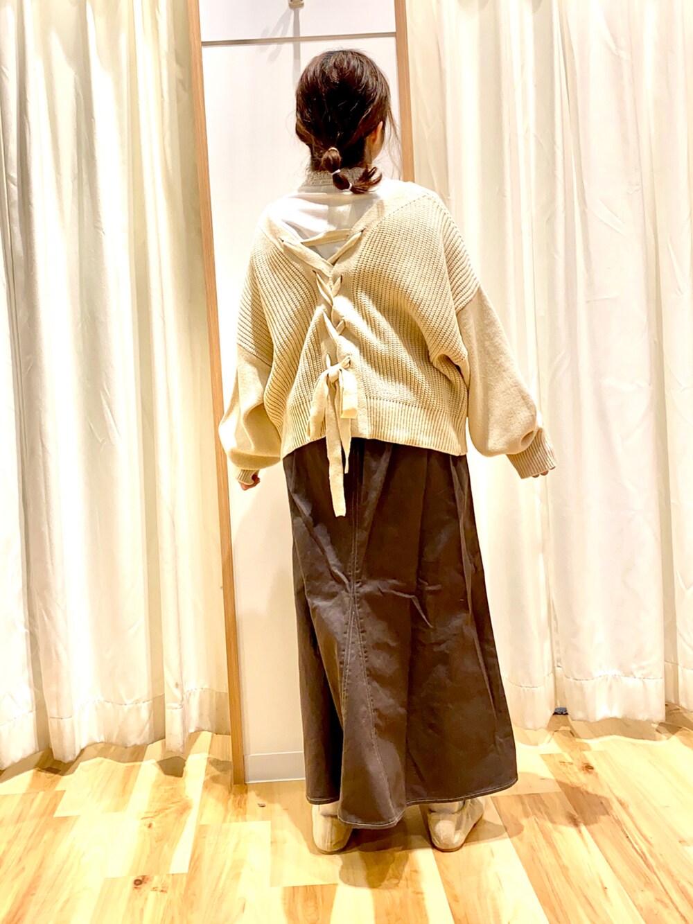 ホワイト系のカーディガン/ボレロ、ホワイト系のTシャツ/カットソー、グレー系のスカートを着用したレディースの冬コーディネートの2枚目の写真