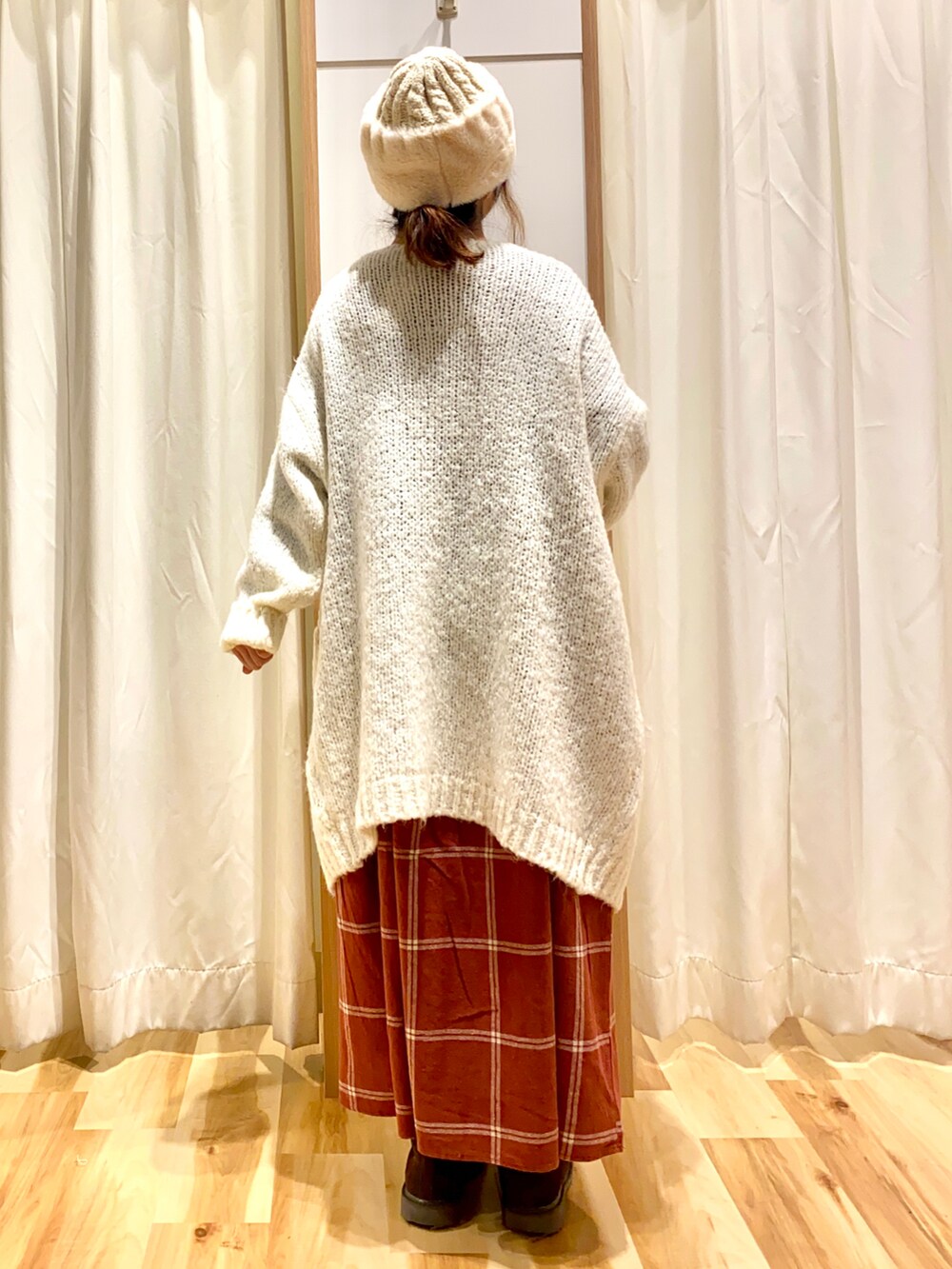 レッド系のワンピース、ホワイト系のカーディガン/ボレロ、ブラウン系のブーツを着用したレディースの冬コーディネートの2枚目の写真