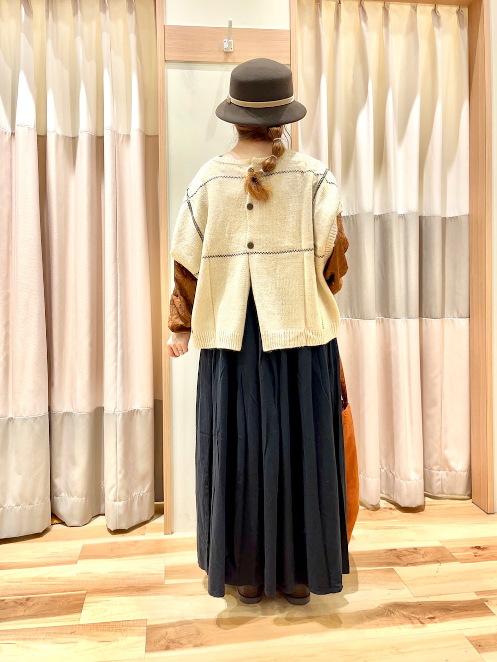 ホワイト系のベスト、ブラウン系のTシャツ/カットソー、ブラック系のスカートを着用したレディースの秋コーディネートの2枚目の写真