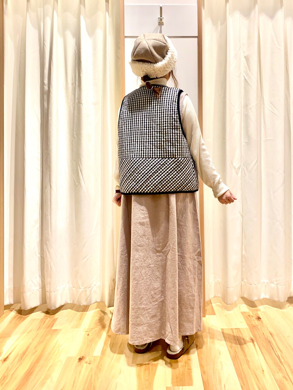 ブラウン系のワンピース、ホワイト系のニット/セーター、グレー系のベストを着用したレディースの冬コーディネートの2枚目の写真