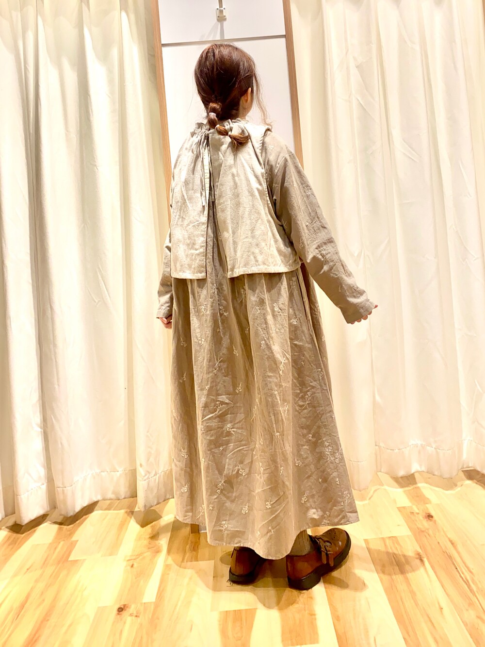 ホワイト系のベスト、ベージュ系のワンピース、イエロー系のドレスシューズを着用したレディースの春コーディネートの2枚目の写真