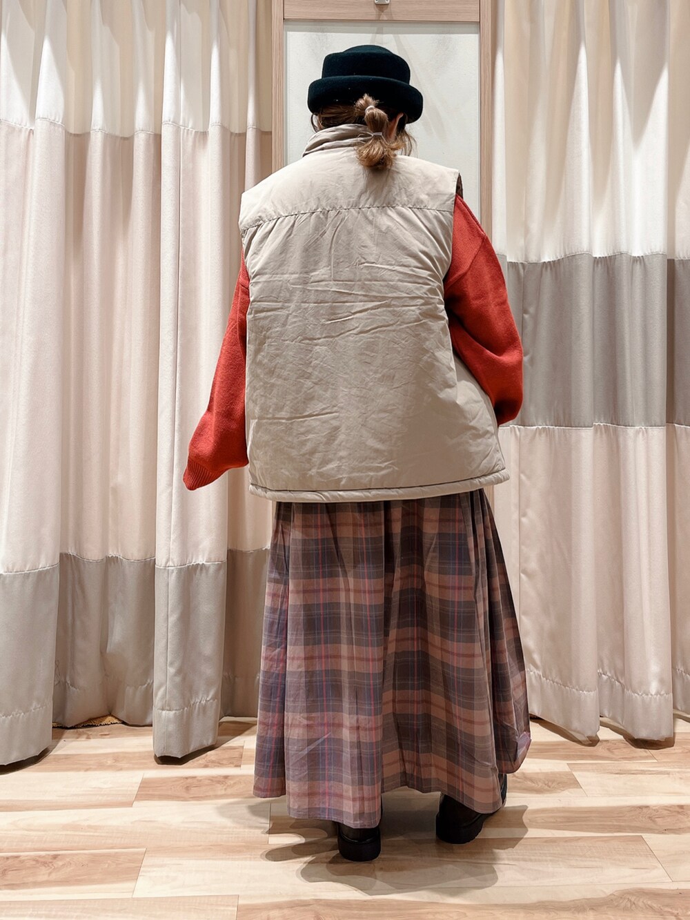 ベージュ系のベスト、レッド系のニット/セーター、ピンク系のスカートを着用したレディースの秋コーディネートの2枚目の写真