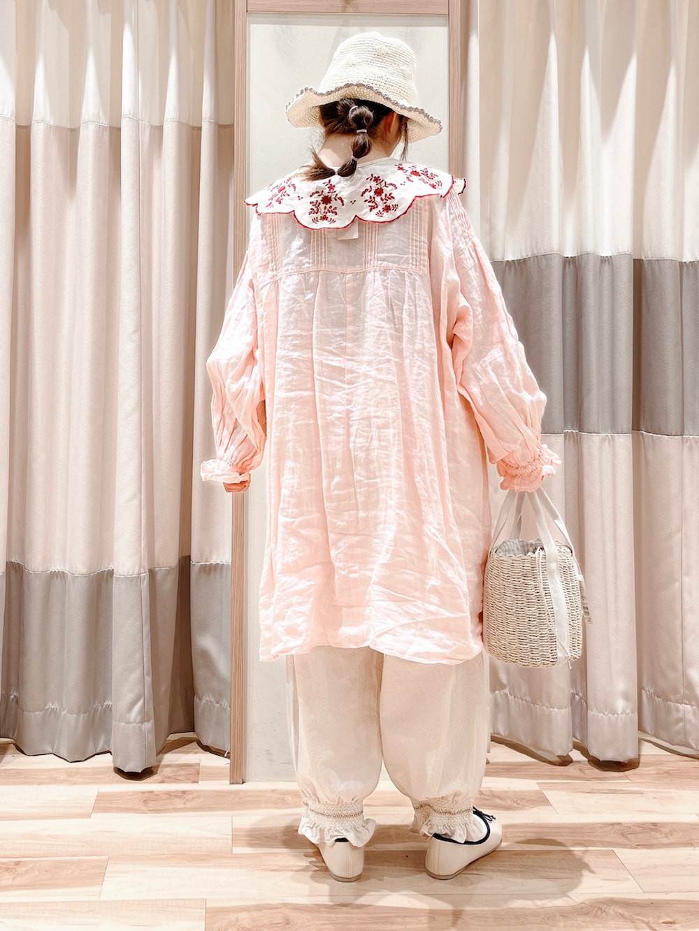 ピンク系のチュニック、ホワイト系のその他パンツ、ホワイト系のハンドバッグを着用したレディースの春コーディネートの2枚目の写真