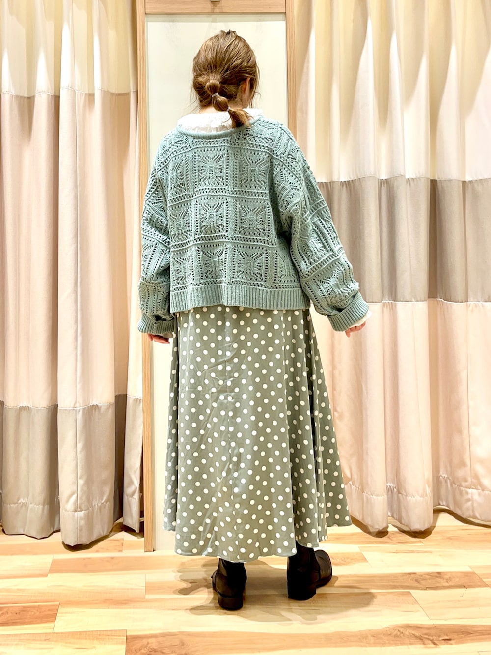 グリーン系のニット/セーター、ホワイト系のシャツ/ブラウス、グリーン系のスカートを着用したレディースの冬コーディネートの2枚目の写真