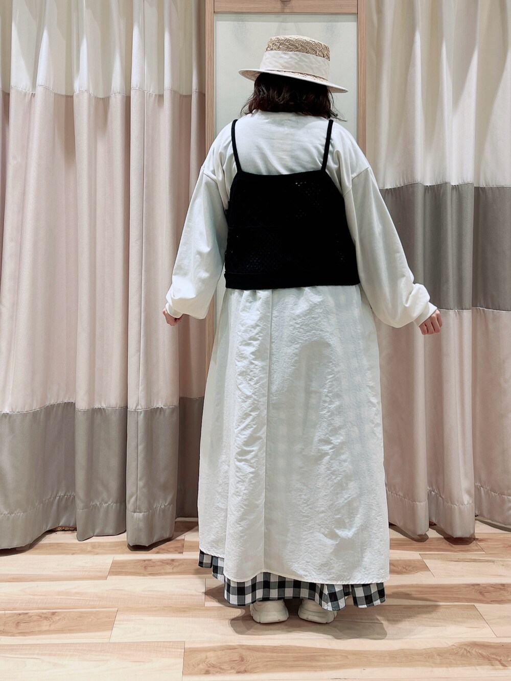 ブラック系のキャミソール、ホワイト系のワンピース、ブラック系のスカートを着用したレディースの春コーディネートの2枚目の写真